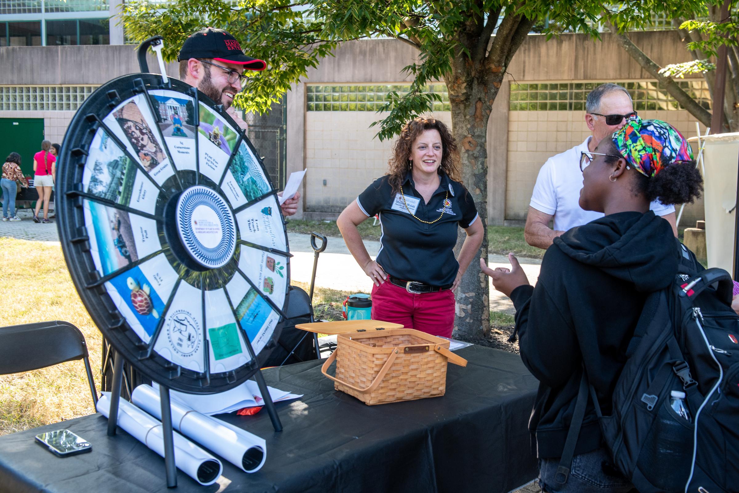 Faculty at event doing a spin the wheel trivia challenge on Agriculture related topics.